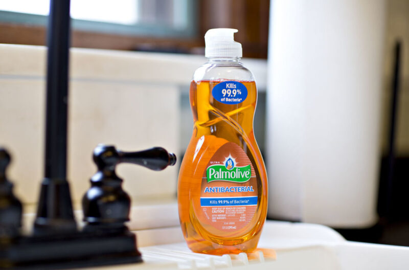 Bottle of dish soap sitting on the edge of a sink