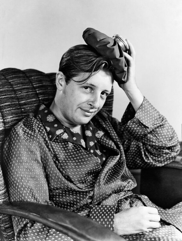 Man sitting in a chair while holding a cold compress on his head