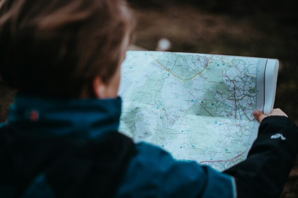 photo from over the shoulder of man outdoors looking at map